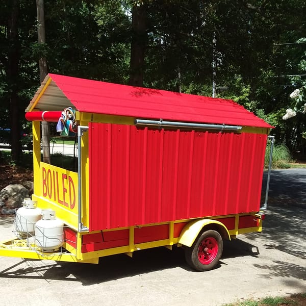A bright red and yellow food trailer with "BOILED" on the side, parked on asphalt.