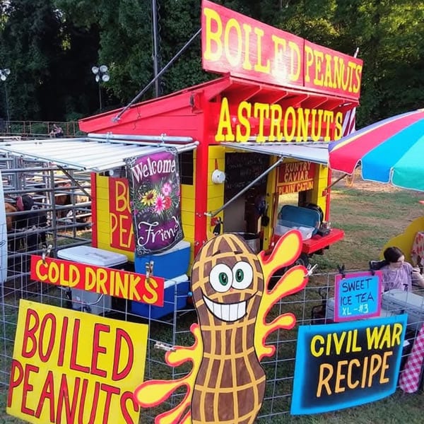 A vibrant red and yellow "Boiled Peanuts" stand with signs for "Cold Drinks" and "Civil War Recipe."