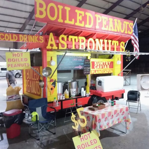 A vibrant red and yellow food truck selling "Boiled Peanuts" and "Astronuts" with an American flag.